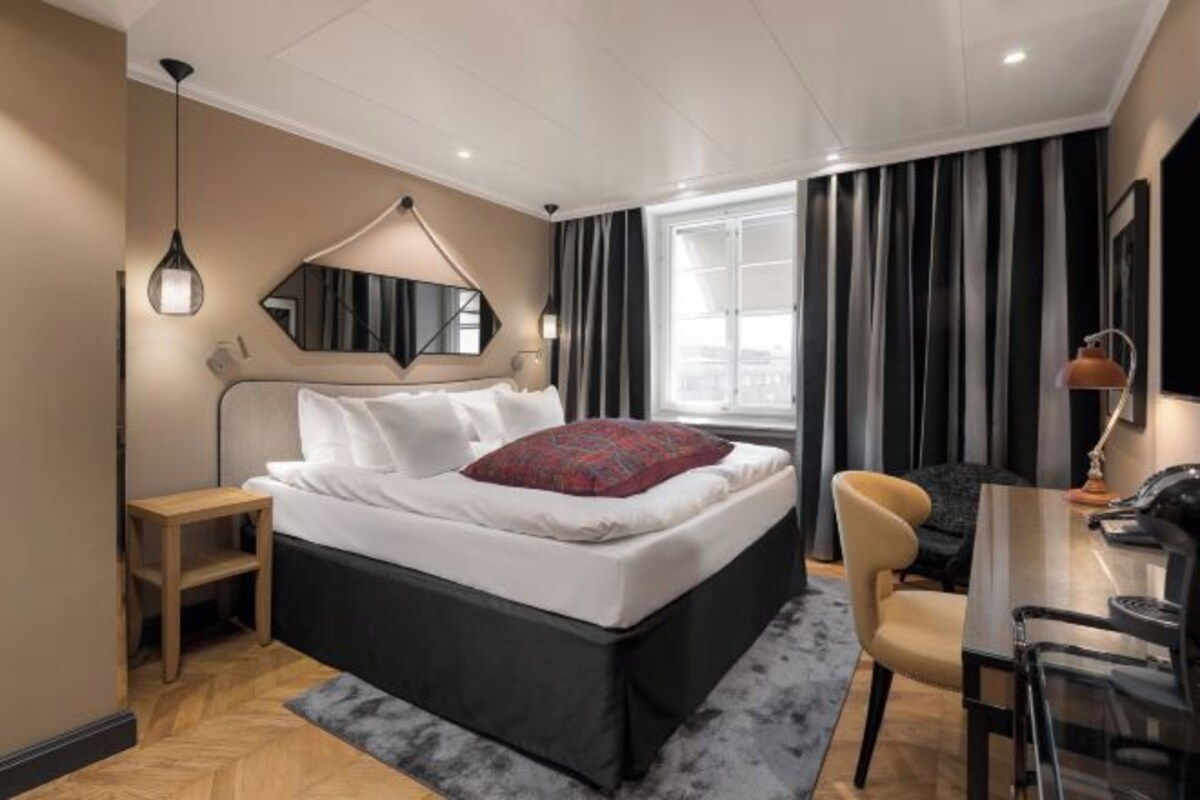 Een moderne hotelkamer met een groot bed, een bureau en een stoel.