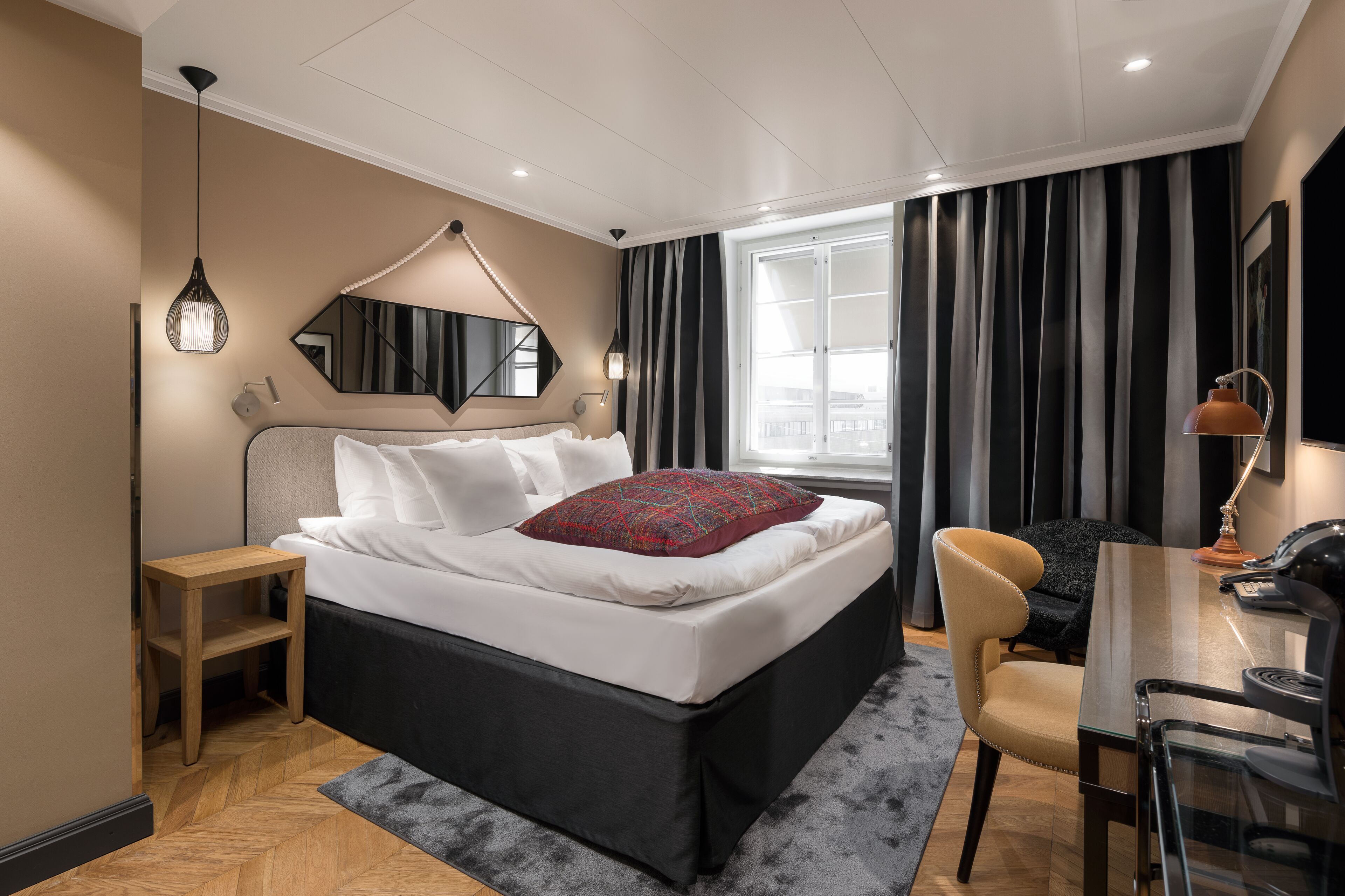 A modern hotel room with a large bed, a desk, and a chair.