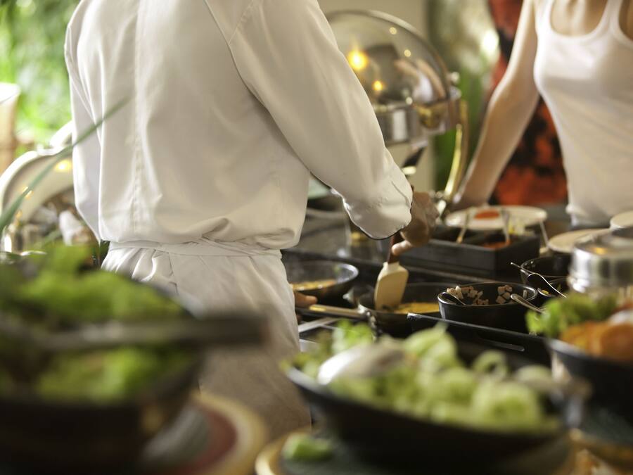 A chef preparing food in a kitchen with various dishes and cooking utensils.