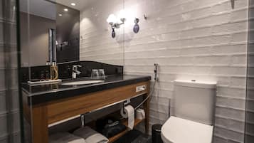 Un baño moderno con encimera negra, lavabo, espejo, inodoro y ducha.
