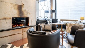 Un salon moderne doté d’une cheminée, de fauteuils en cuir et offrant une vue sur le ciel.