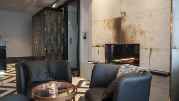 A modern lounge area with leather seating, a glass coffee table, and a fireplace.