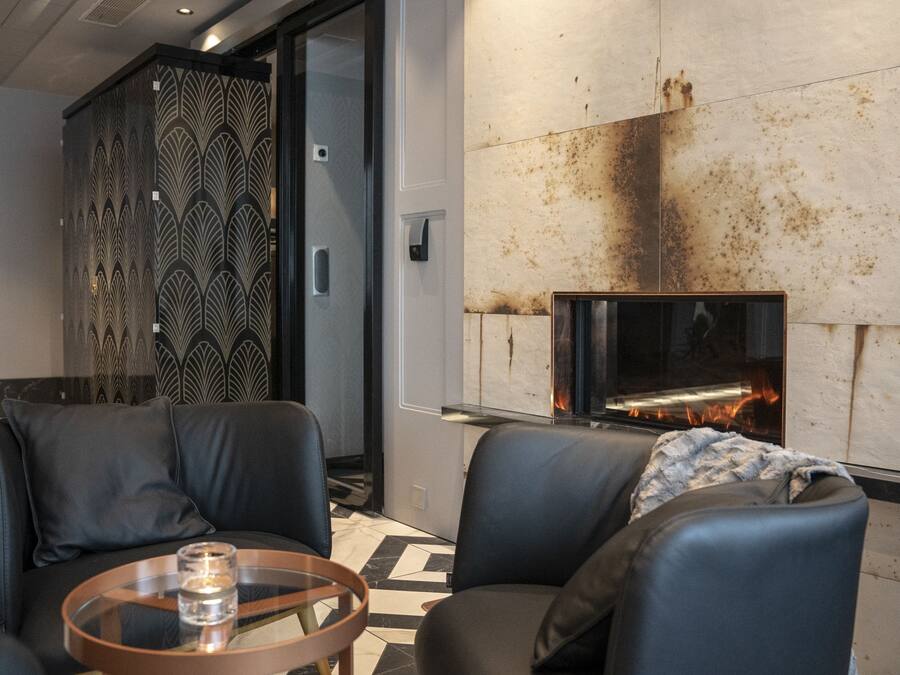 A modern lounge area with leather seating, a glass coffee table, and a fireplace.