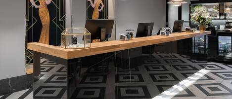 A reception desk with a glass enclosure, a telephone, and a coffee machine.