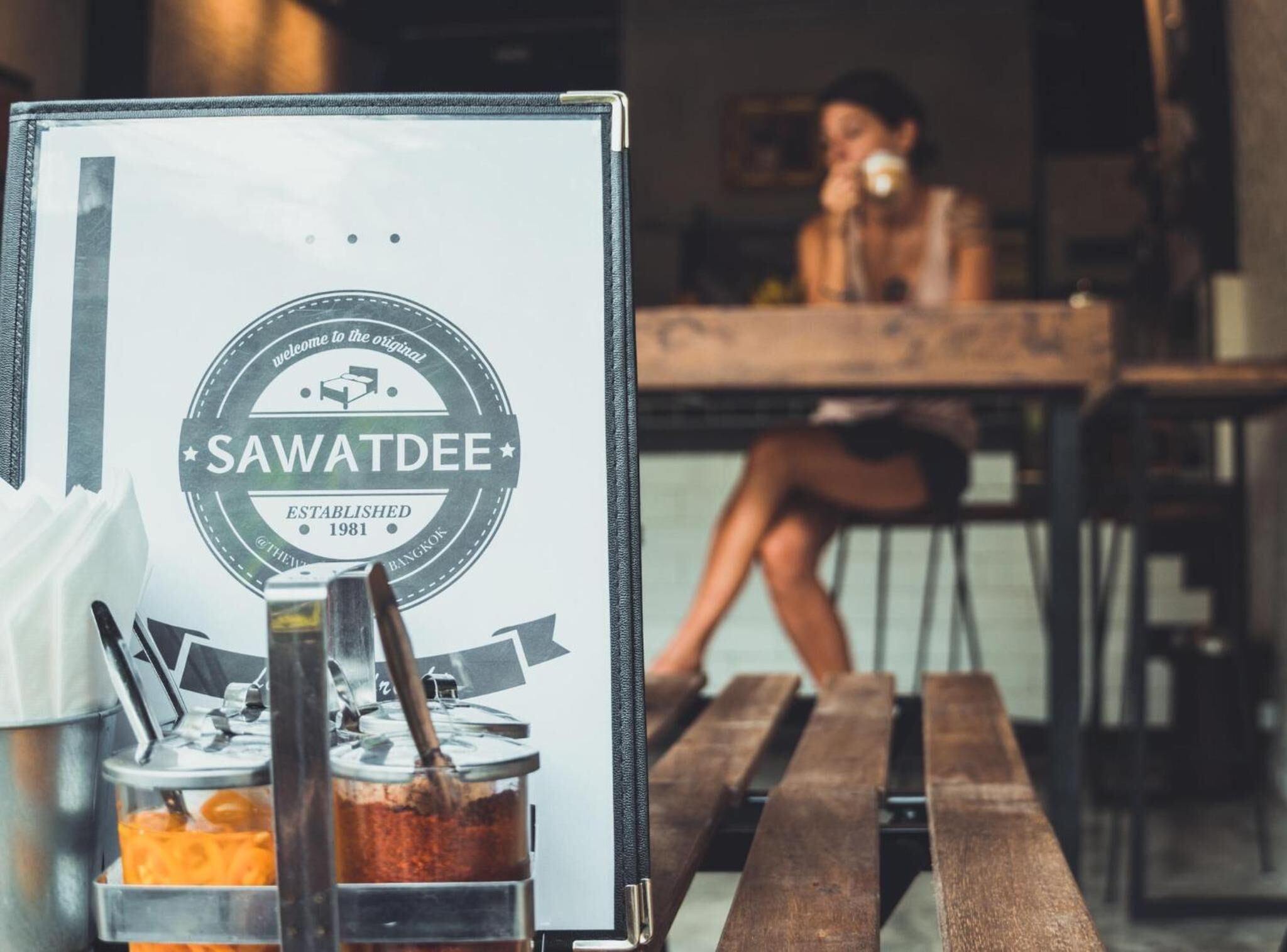 A coffee shop interior with a wooden table and a person sitting at a table.