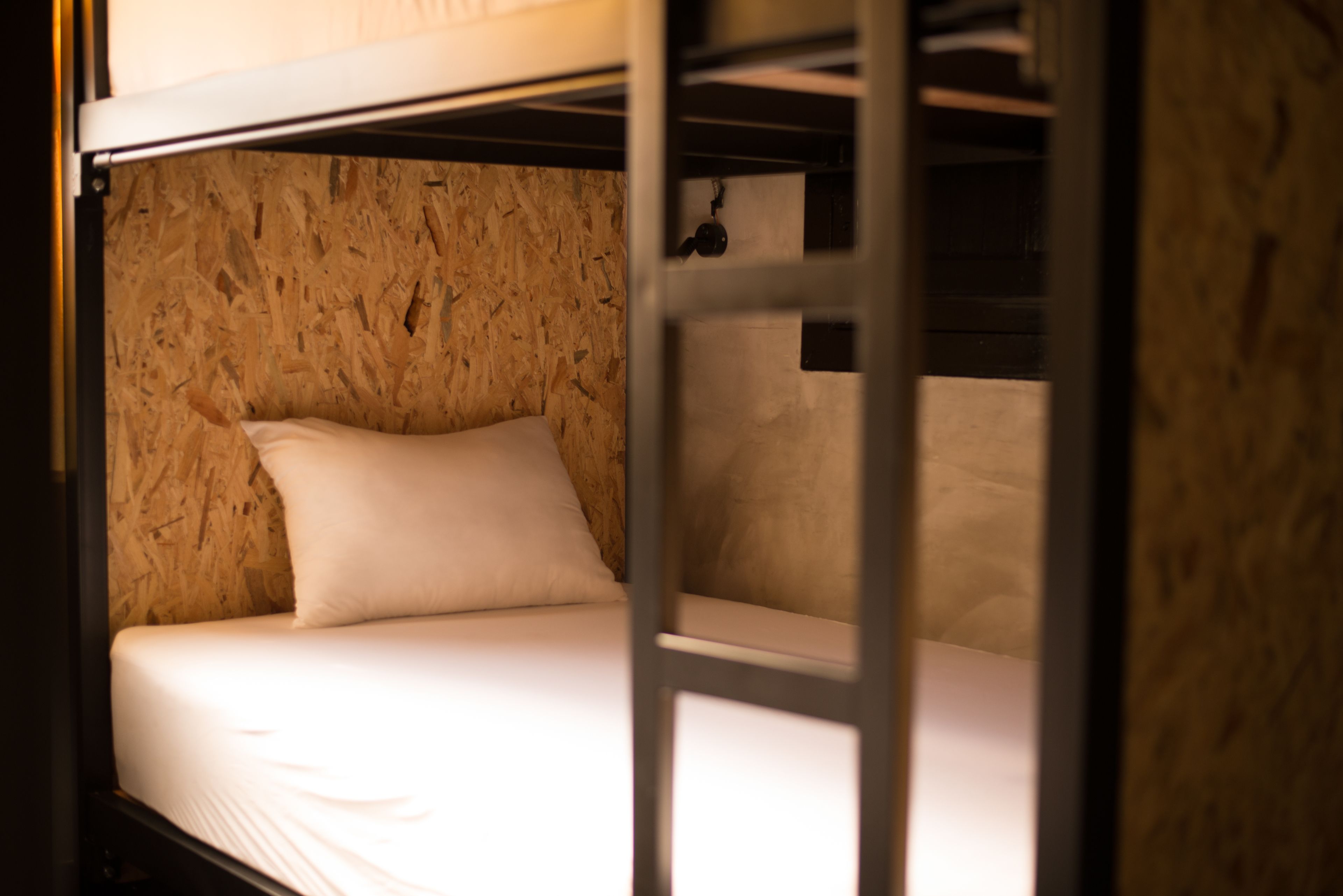 A bunk bed with a wooden wall and a white mattress.