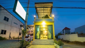A small, modern building with a bright interior, a covered entrance, and a visible staircase leading to the entrance. - Mango Home 102 (Hua Hin)