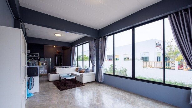 A modern living room with a sofa, a coffee table, and a large window with curtains. - Mango Home 102 (Hua Hin)