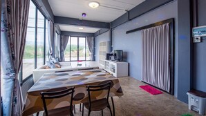 A modern room with a dining table, chairs, a sofa, a television, and a cabinet. - Mango Home 102 (Hua Hin)