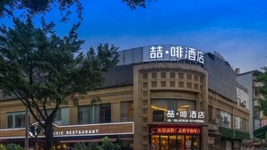 Un hôtel à la façade moderne, avec une signalétique en anglais et en chinois, et un restaurant bien visible nommé « Music Restaurant » situé au rez-de-chaussée.