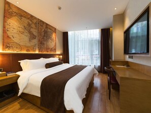 Ein Hotelzimmer mit einem großen Bett, einem Schreibtisch, einem Fernseher und einer Karte an der Wand.