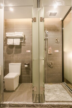 Ein modernes Badezimmer mit Duschkabine aus Glas, Toilette und Handtuchhalter mit Handtüchern.