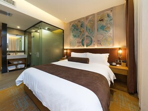 A hotel room with a large bed, a glass-enclosed shower area, a wooden vanity with a mirror, and a large world map on the wall. - James Joyce Coffetel Dongxiaonan (Guangzhou)