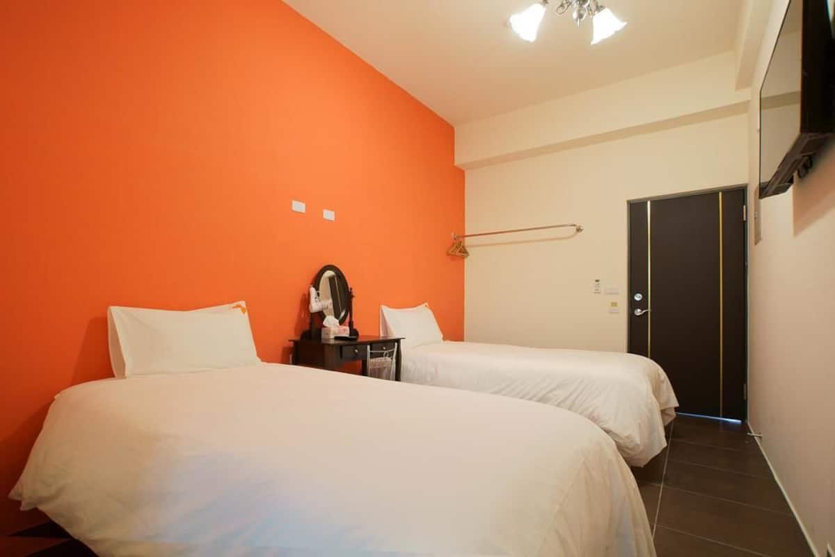 Een hotelkamer met twee bedden, een nachtkastje, een spiegel en een deur.