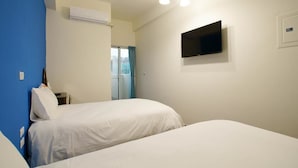 Une chambre d’hôtel avec deux lits, un téléviseur à écran plat fixé au mur et un appareil de climatisation.