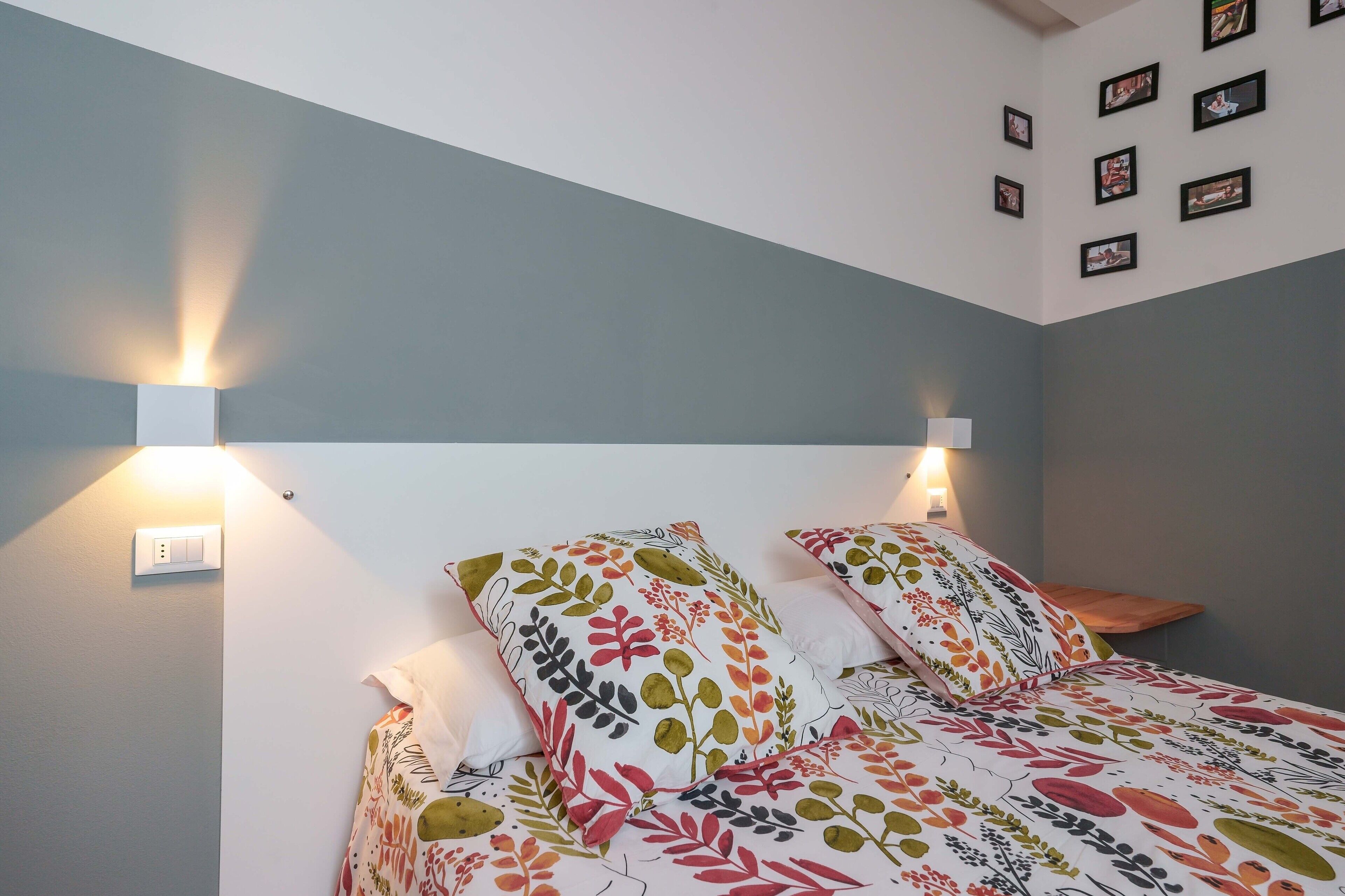A bedroom with a bed, two bedside lamps, and a wall-mounted light fixture.
