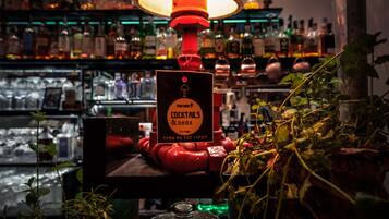 Eine Barbereich mit Schild für Cocktails und Betten, umgeben von Regalen voller Flaschen und Gläsern.