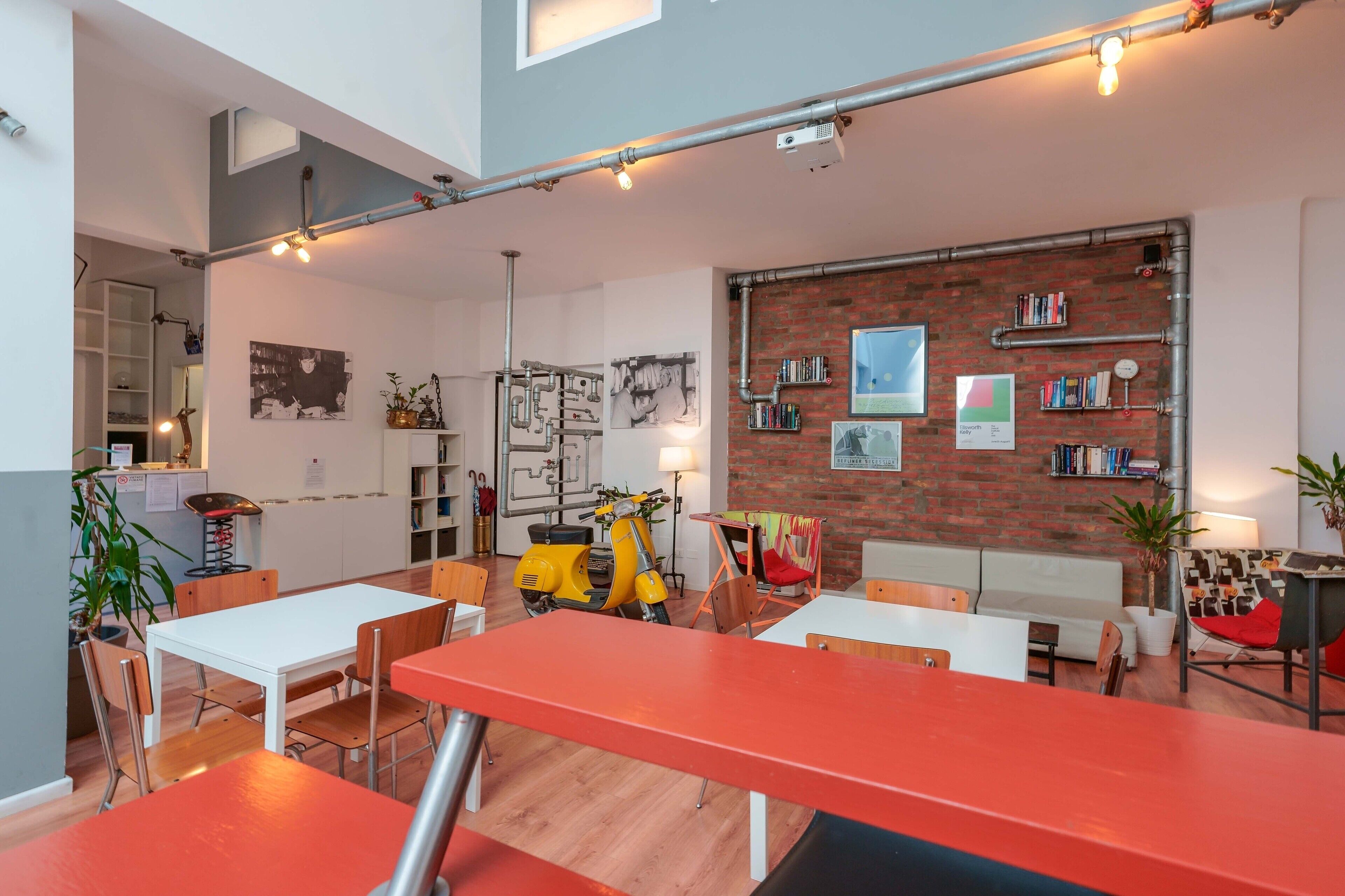 A modern interior with a dining area, a yellow scooter, and a brick wall with bookshelves.