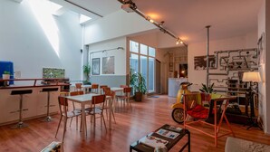 A spacious living area with a kitchen, dining table, and chairs. There is a motorcycle, a lamp, and a plant in the room.