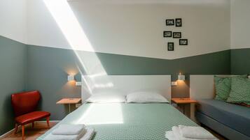 Une chambre à coucher avec un lit, un fauteuil rouge, un canapé et des lampes fixées au mur.