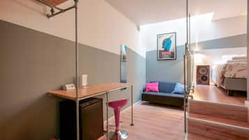 Una habitación moderna con un escritorio de madera, una silla rosa, un sofá y una cama.