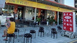A building with multiple floors, outdoor seating area, and a signboard.
