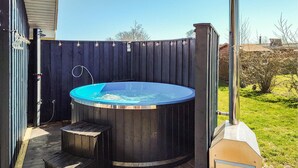 A hot tub surrounded by a wooden deck, with a chimney and a grill in the background. - Gorgeous home in Hadsund with kitchen (Hadsund)