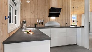 A modern kitchen with wooden paneling, a black countertop, white cabinets, and a built-in oven. - Gorgeous home in Hadsund with kitchen (Hadsund)