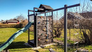 A playground with a slide, climbing wall, and swings. - Gorgeous home in Hadsund with kitchen (Hadsund)