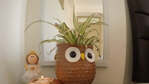 Una habitación con un búho decorativo, una pequeña figurita, un mantel de encaje y un cuadro en la pared.