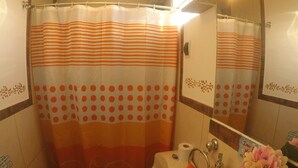 Un baño con cortina de ducha, lavamanos e inodoro.