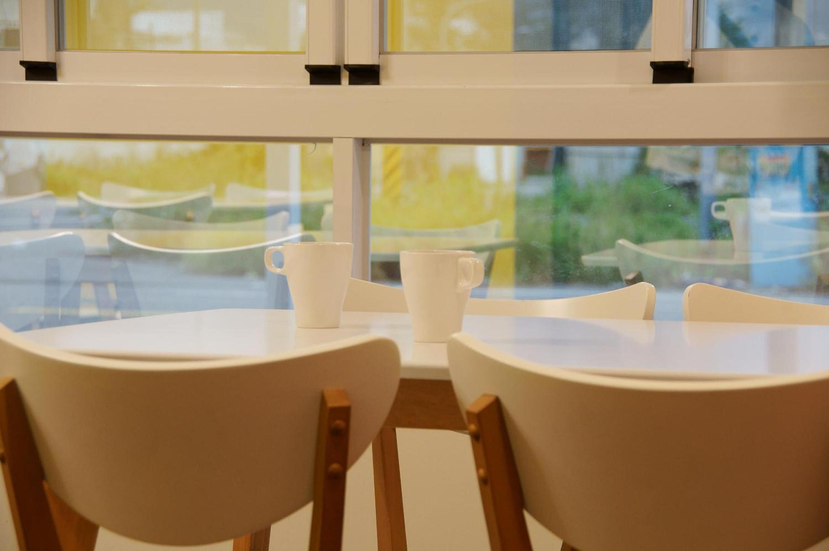 A table and chairs in a room with a view through a window.