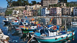 Un port avec des bateaux amarrés, des bâtiments en arrière-plan et un ciel dégagé.