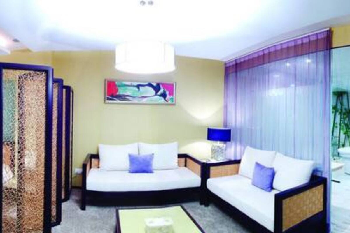 A hotel room with a bed, a sofa, a desk, and a large window with a view of a pool.