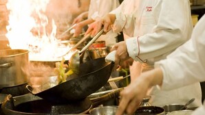 Chefs cooking in a professional kitchen with stainless steel cookware and a visible flame. - Koriyama View Hotel (Koriyama)