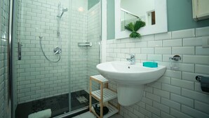 A bathroom with a glass shower enclosure, a white sink with a blue soap dish, and a mirror above the sink. - Casa Minna (Sant'Agnello)