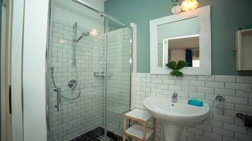 A bathroom with a glass-enclosed shower, a white sink, and a mirror above it.