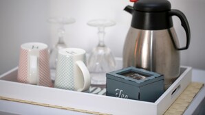 A tray with a stainless steel coffee pot, two patterned mugs, a glass carafe, and a small box labeled "Tea". - Casa Minna (Sant'Agnello)