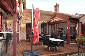 An outdoor patio with tables and chairs, a covered seating area, and a building with a tiled roof. - Maison Du Prince De Conde (Charroux)