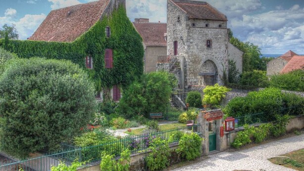 Un bâtiment historique aux murs recouverts de lierre et doté d’une tour en pierre.