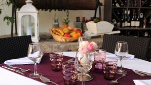 Une table mise pour un repas, avec des verres à vin, un panier de fruits et une bougie.
