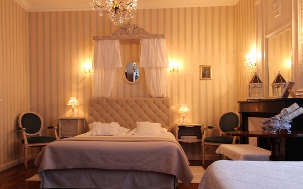 A hotel room with a large bed, two bedside tables, a chair, a small table, and a decorative mirror. - Maison Du Prince De Conde (Charroux)