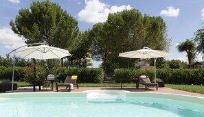 Una piscina al aire libre de temporada, sombrillas