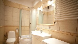 A bathroom with a toilet, a glass-enclosed shower, a sink, and a mirror. - Apartamenty Kazimierz (Kraków)