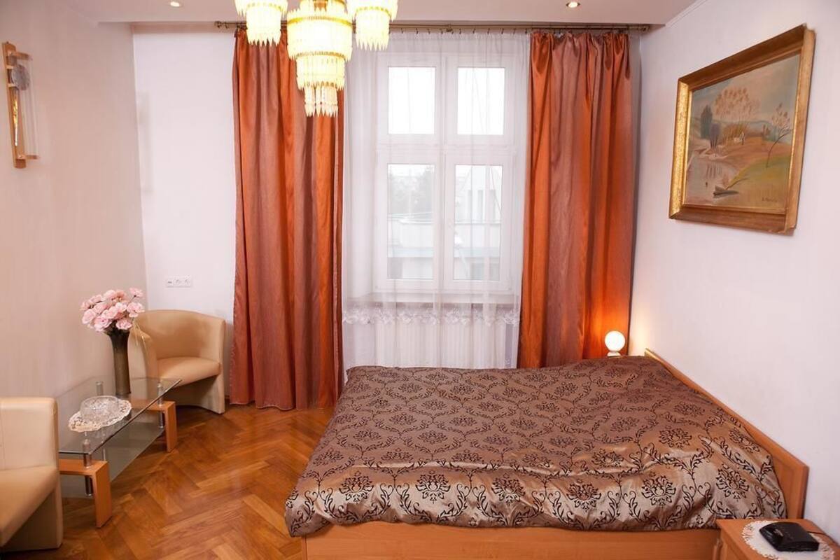 Un dormitorio con una cama grande, una silla, una mesita y un cuadro en la pared.