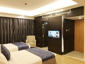 A hotel room with two beds, a TV, a chair, and a wardrobe. - The Days Dhaka (Dhaka)