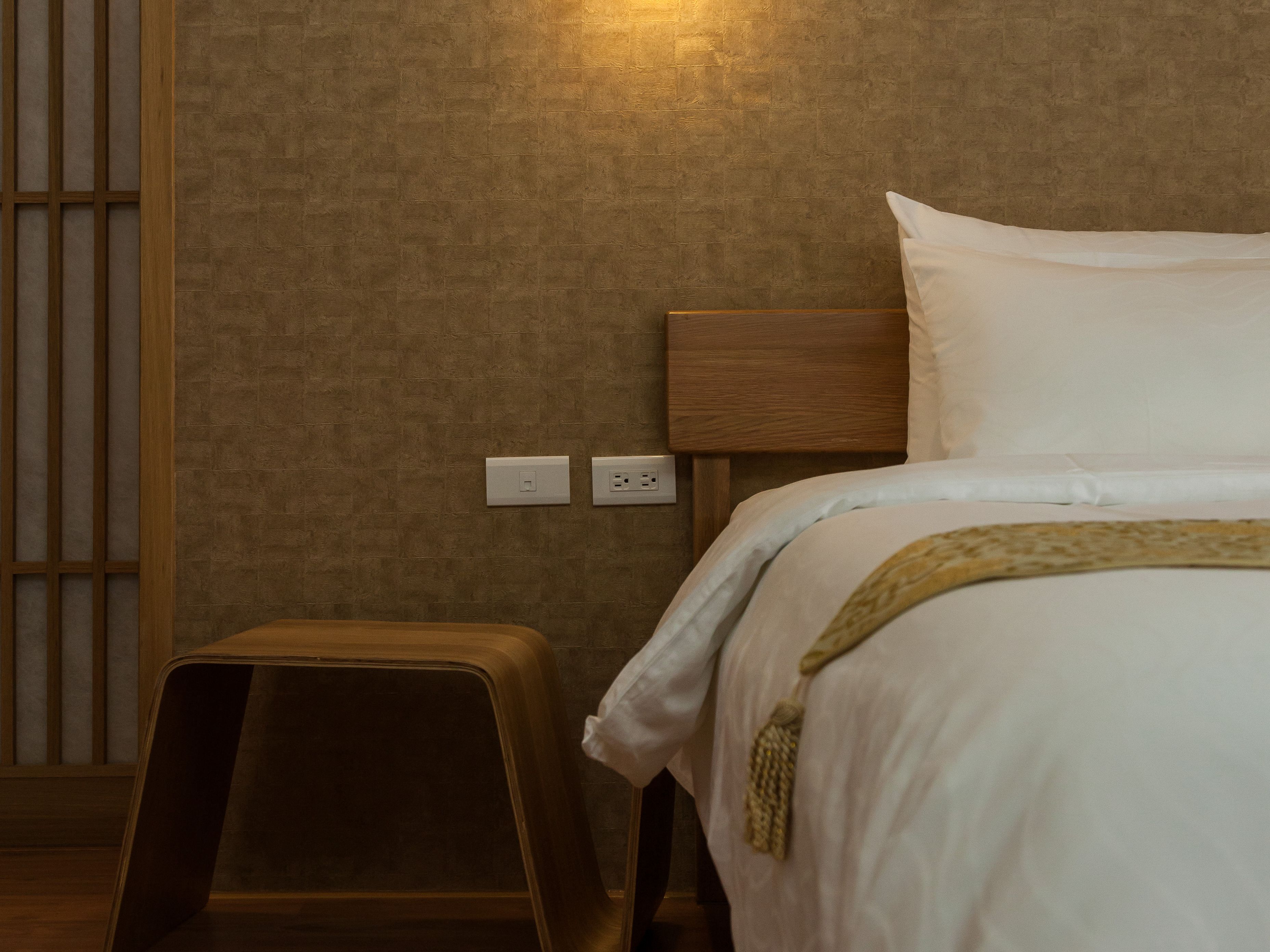 Un dormitorio con una cama, una mesita de noche y una lámpara en la pared.