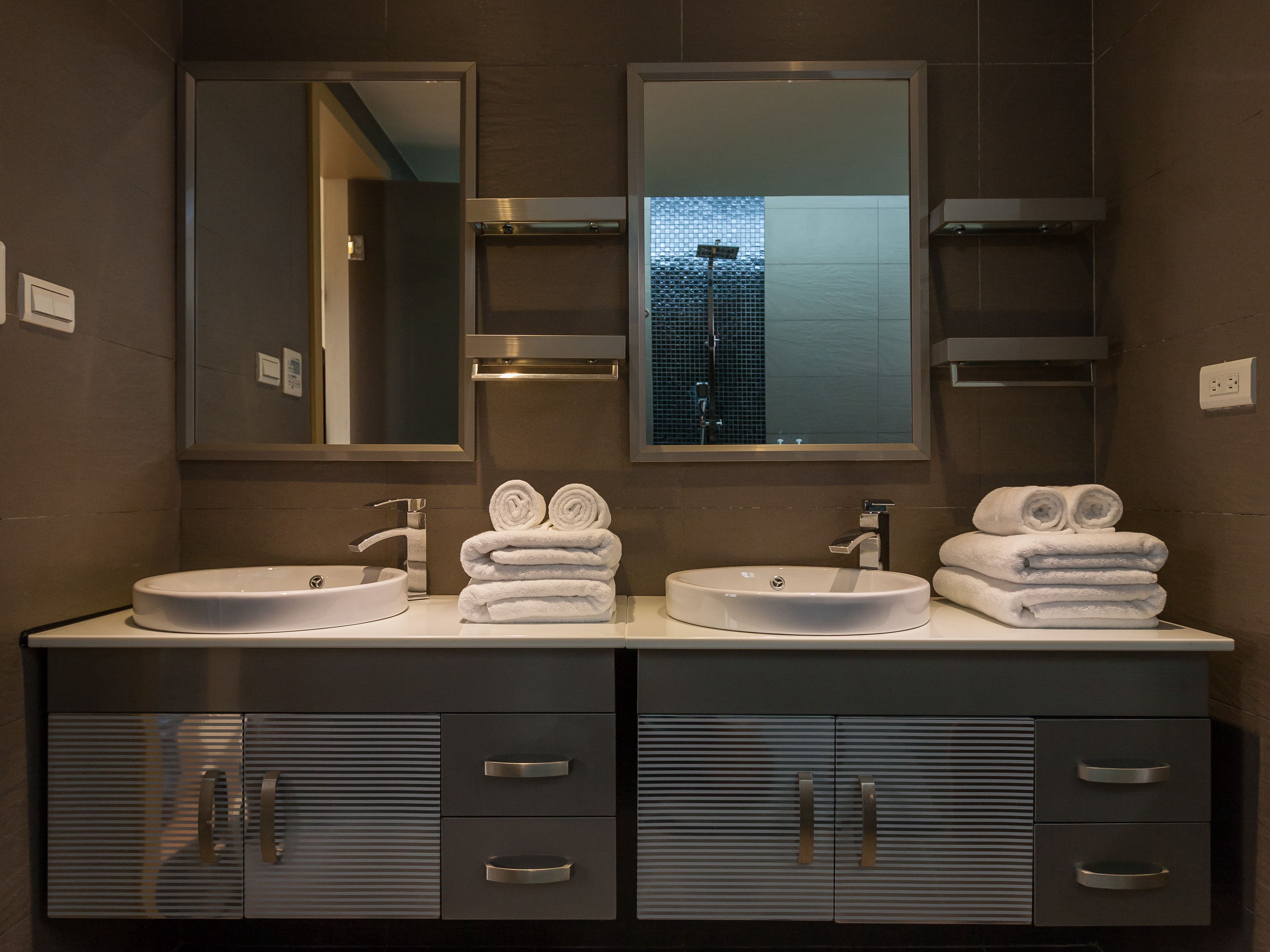 Un baño moderno con dos lavamanos, un espejo grande y vistas a un edificio por la ventana.