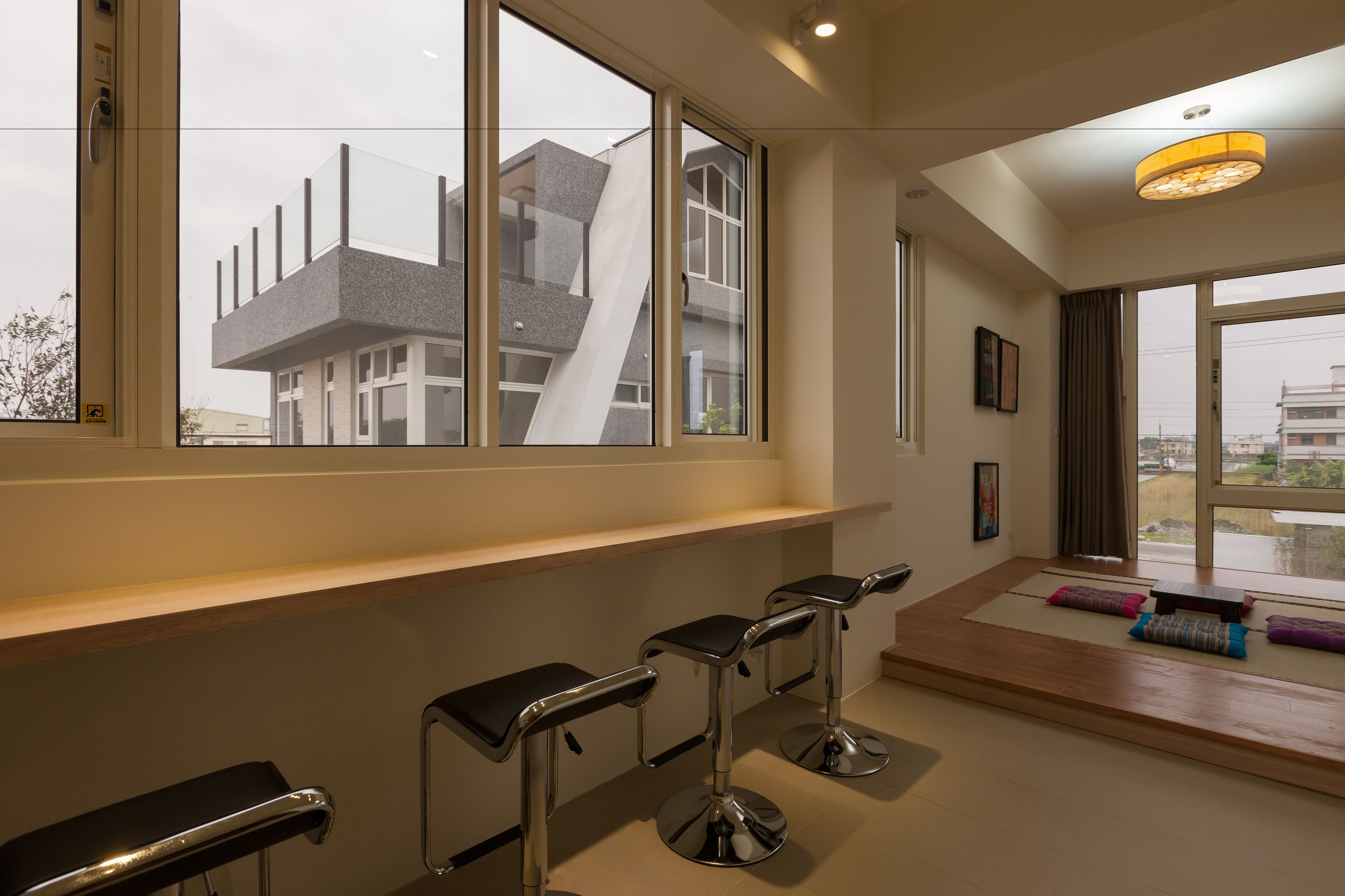 A modern interior with large windows, a wooden bench, and a bar area with stools.