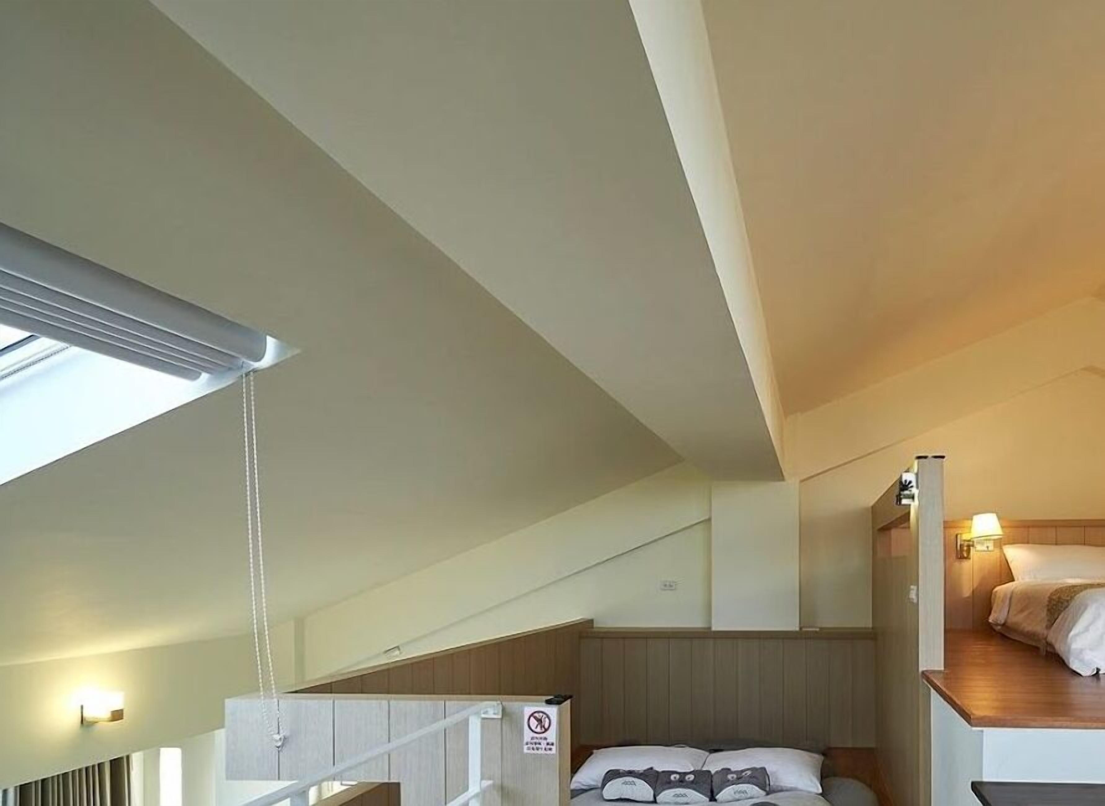 Une chambre d’hôtel compacte avec un lit superposé, une lucarne et un escalier.